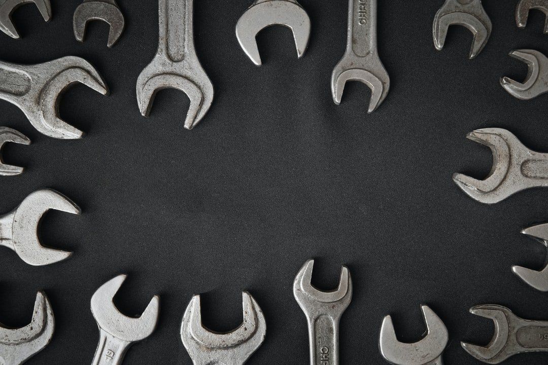 Wrenches arranged in a circle on a dark gray surface, framing an empty space.