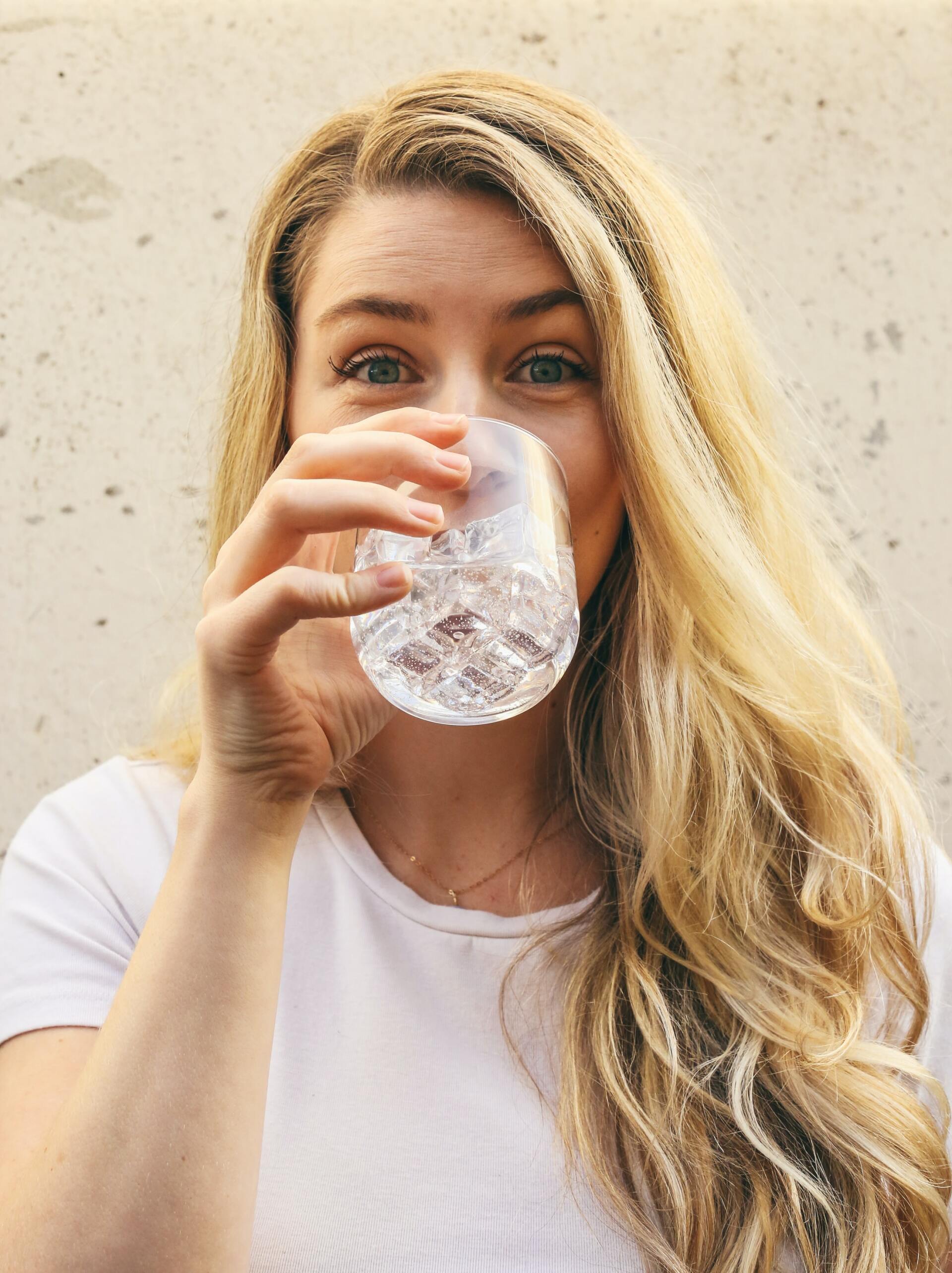 A woman is drinking water from a glass.