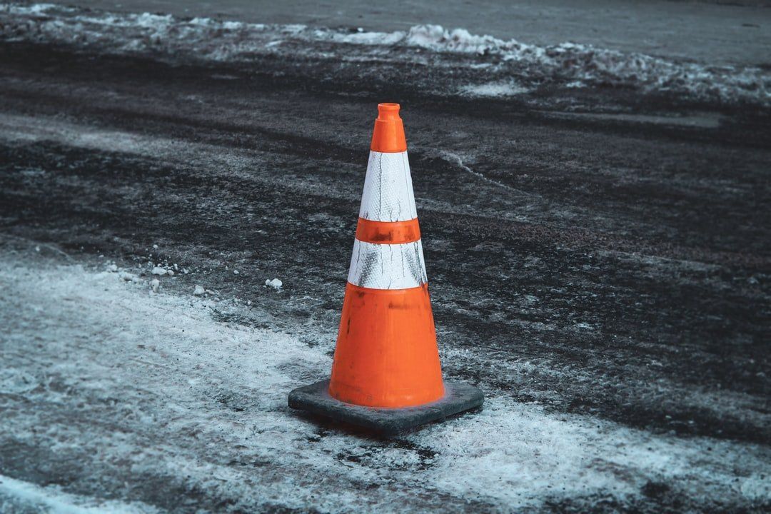 Orange traffic cone on a snowy, icy road surface