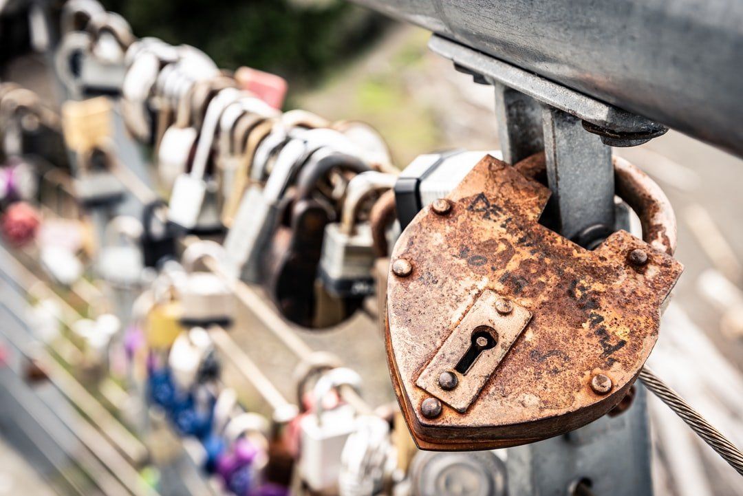 A close up of a rusty heart shaped padlock on a bridge.