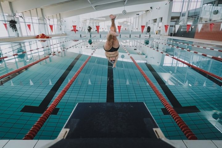 A man is jumping into a swimming pool from a diving board.