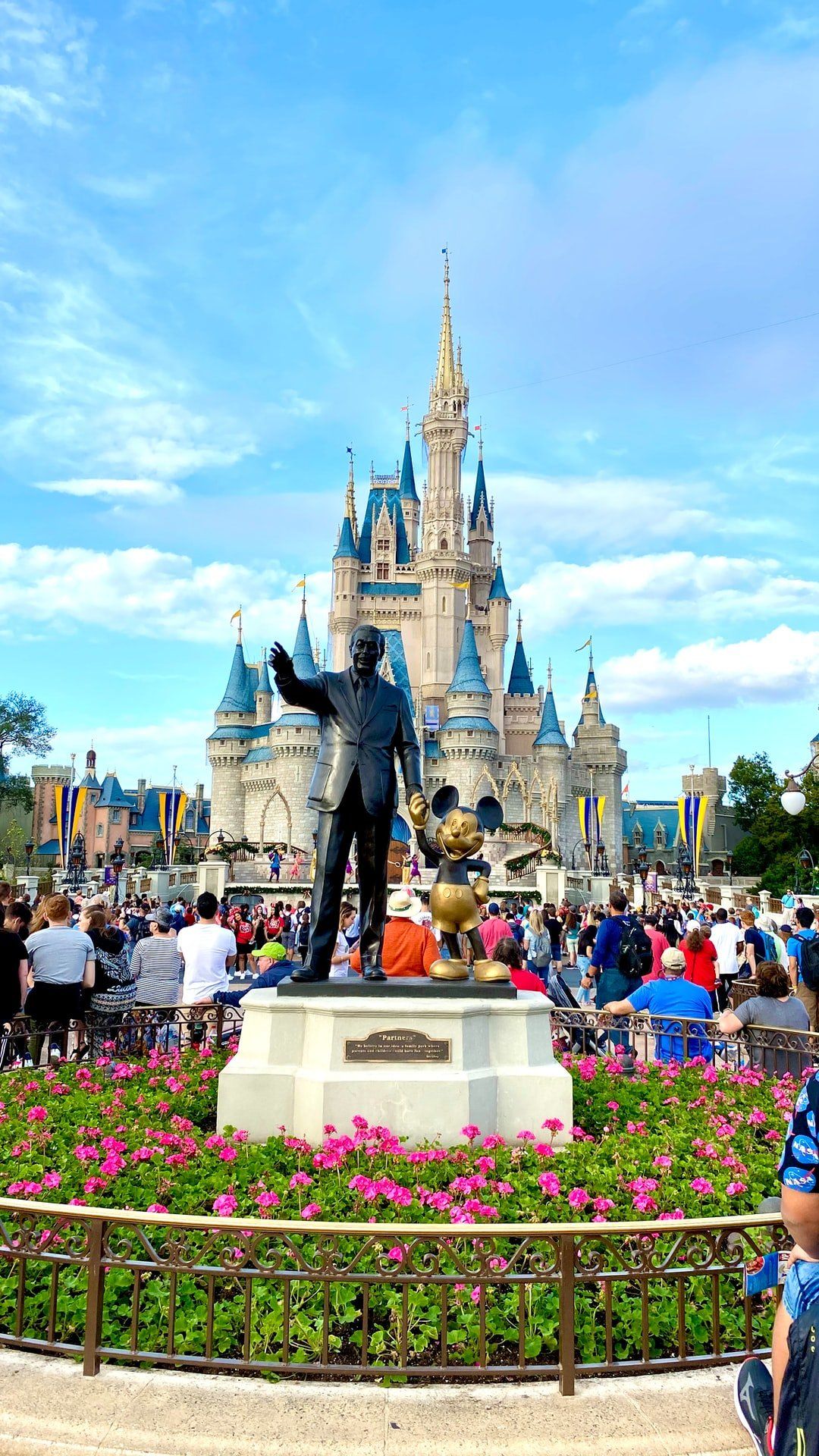 A statue of walt disney and mickey mouse in front of a castle at disney world.