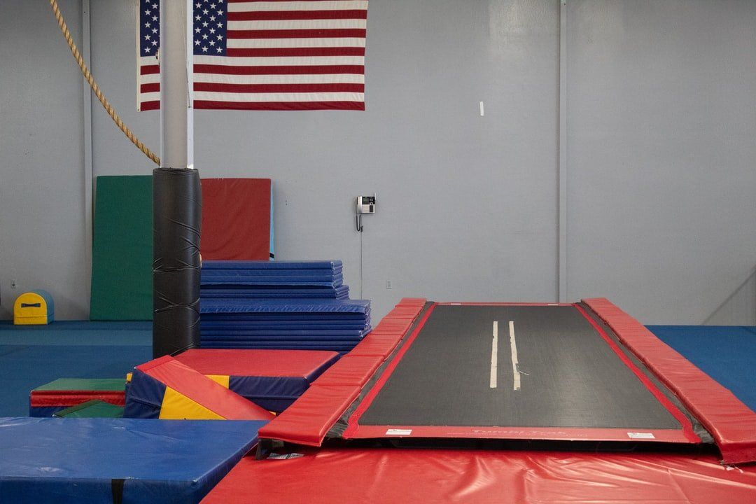 A trampoline in a gym with an American flag on the wall.