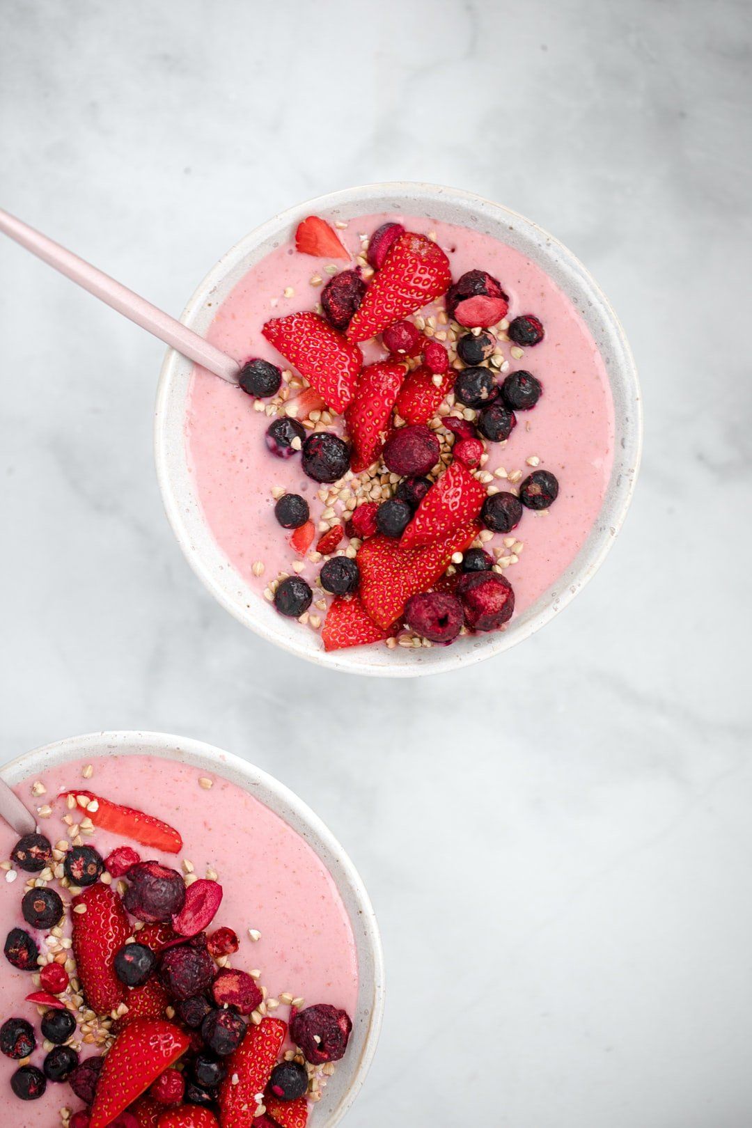 A smoothie bowl with dairy yoghurt topped with mixed berries and granola.