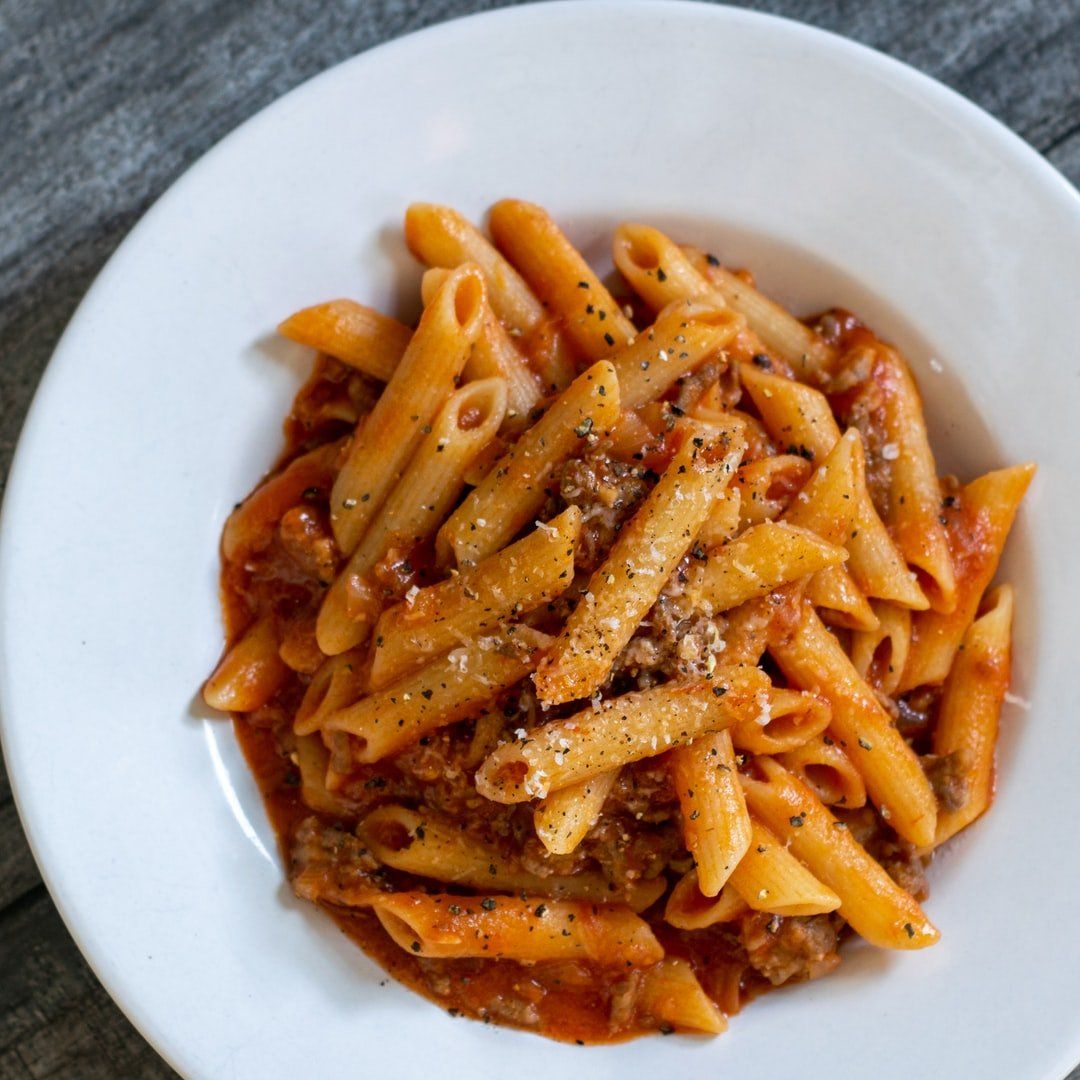 A white bowl filled with pasta and sauce on a table