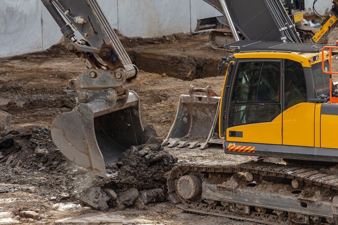 Yellow excavator digging in dirt on a construction site.
