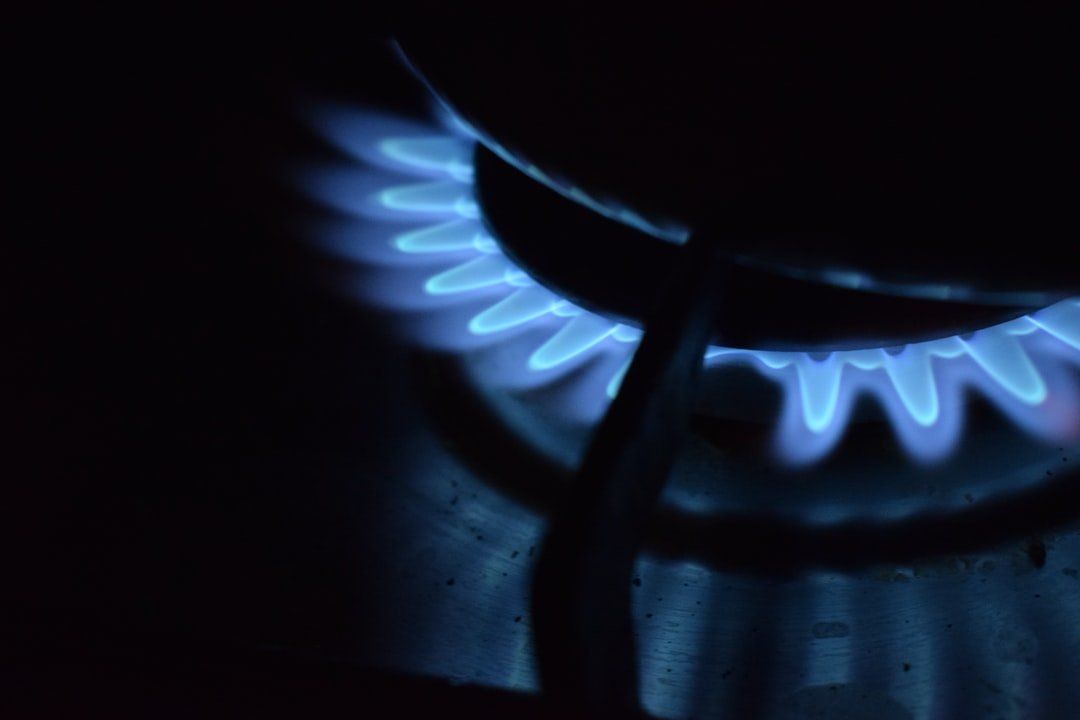 Fiamma blu del fornello a gas che brucia su un piano cottura scuro
